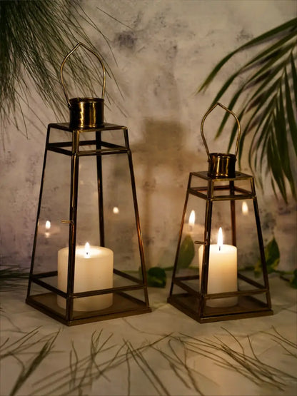 Two metal lanterns with candles inside on a surface with a leafy background