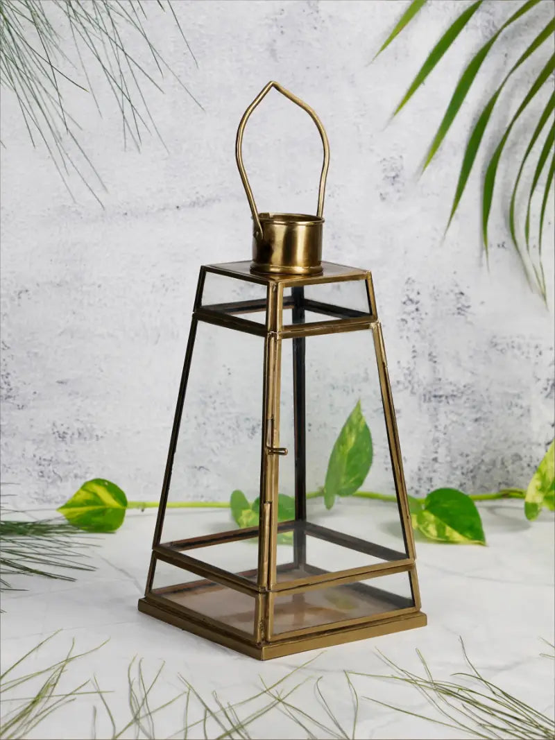 Bronze lantern with glass cover on a light background with green leaves
