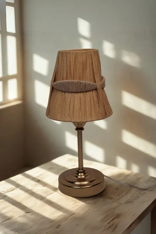 Table lamp with a brown shade on a wooden surface, casting shadows.
