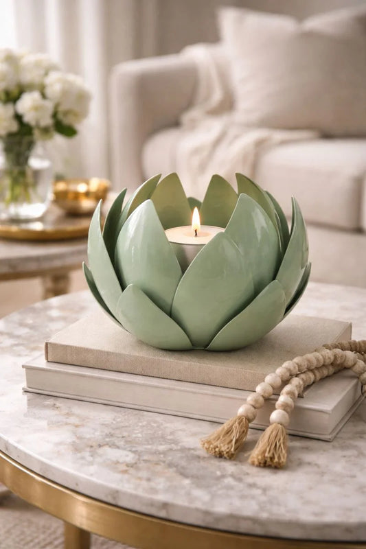 Decorative candle holder shaped like an artichoke on a marble table with books and a tassel.