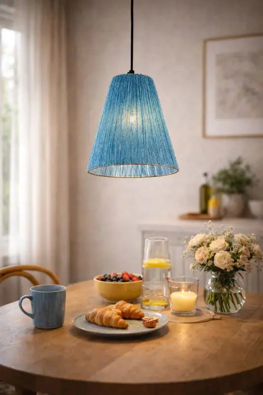 Blue pendant light over a dining table with breakfast items and decor.