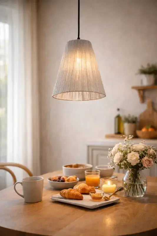 Dining table with breakfast setting and pendant light in a bright room.