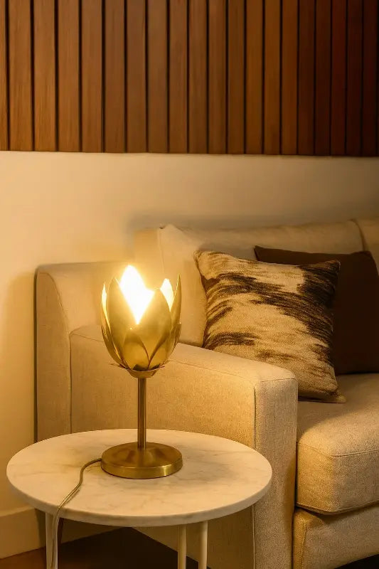 Gold table lamp on a marble side table next to a beige sofa with patterned cushions.