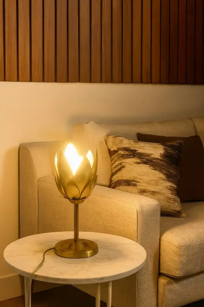 Gold table lamp on a marble side table next to a beige sofa with patterned cushions.